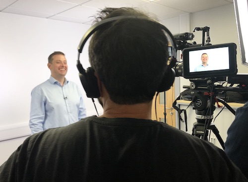 man with a video camera filming a person stand against a white background